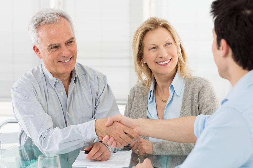 Senior Couple Shaking Hand With Financial Advisor