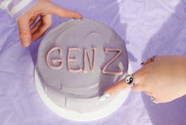 A cake decorated with the words "GEN Z" being touched by two hands.