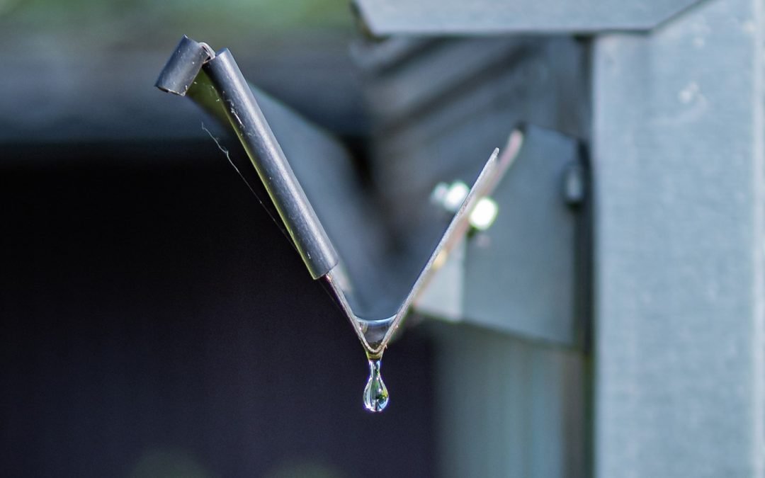 view of a rain gutter looking directly down the length with a droplet of water hanging off